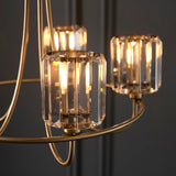 Endon Clementine 5 light pendant close-up showing cut faceted glass shades with lit E14 filament lamps on curved brass plated arms.