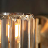 Close-up of Endon Clementine wall light in brass, showing the clear cut faceted glass shade illuminated by a warm E14 bulb.