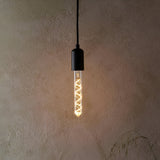 Endon 4W E27 LED filament spiral bulb in a clear tubular glass, warm white glow, fitted in a matte black pendant holder against a textured beige wall.