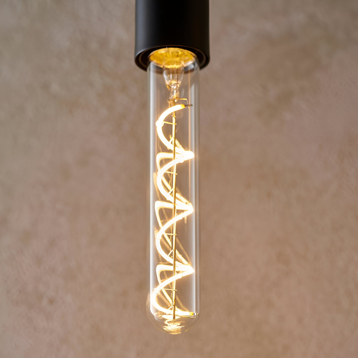 Endon 4W E27 LED filament bulb with clear tubular glass and a warm white spiral filament, shown lit in a matte black pendant holder.