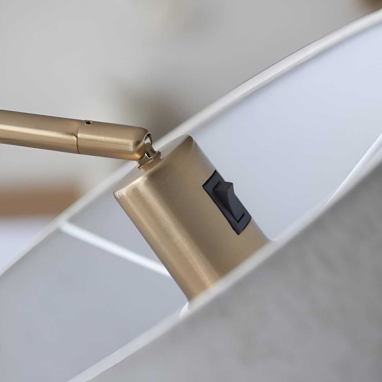 Close-up of the Bevmere Floor Lamp in aged brass, showing the brushed metal joint, rocker switch, and fabric shade edge.