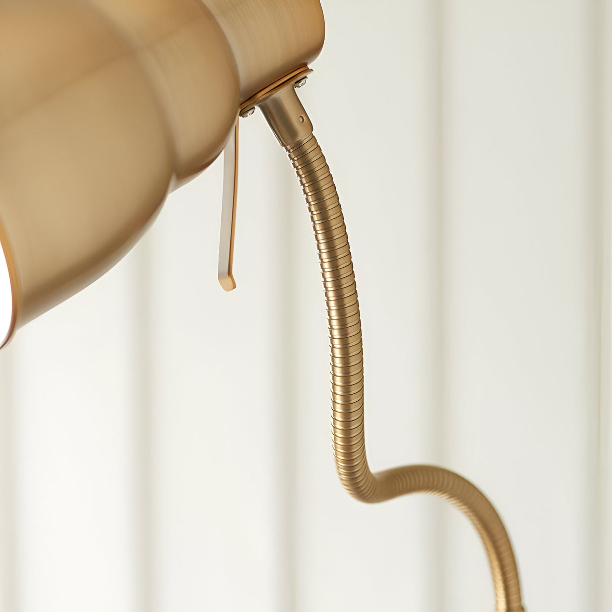 Close-up of the Endon Bevleigh floor lamp showing the brushed brass flexible gooseneck arm and shade in a light interior setting.