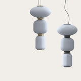 Gold 3-light LED cluster pendant with ribbed white glass shades in oval, cushion and column shapes joined by gold collars, shown as two hanging fixtures on a plain background.