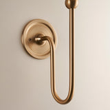 Endon Cliffleigh wall light fitting in brushed aged brass, with a slim upright arm, ball finial, curved hook and round flat back plate.