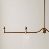 Endon Cliffleigh linear pendant detail in brushed aged brass, showing the curved bar with sphere accent, two visible B22 lamp holders, and drop stem.
