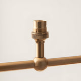 Close-up of an Endon Cliffleigh linear pendant detail in brushed aged brass, showing a B22 lamp holder above a decorative sphere on the bar.