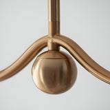 Close-up of the Endon Cliffleigh linear pendant showing the brushed aged brass bar, central stem junction, and decorative sphere detail.