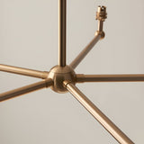 Close-up of the Cliffleigh 5 Light Pendant's brushed aged brass hub, showing radiating metal arms and a B22 lamp holder against a plain light background.