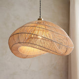 Endon Carlmere cloud-shaped pendant shade in hand-woven natural rattan, suspended from a black cable against a neutral plaster wall.