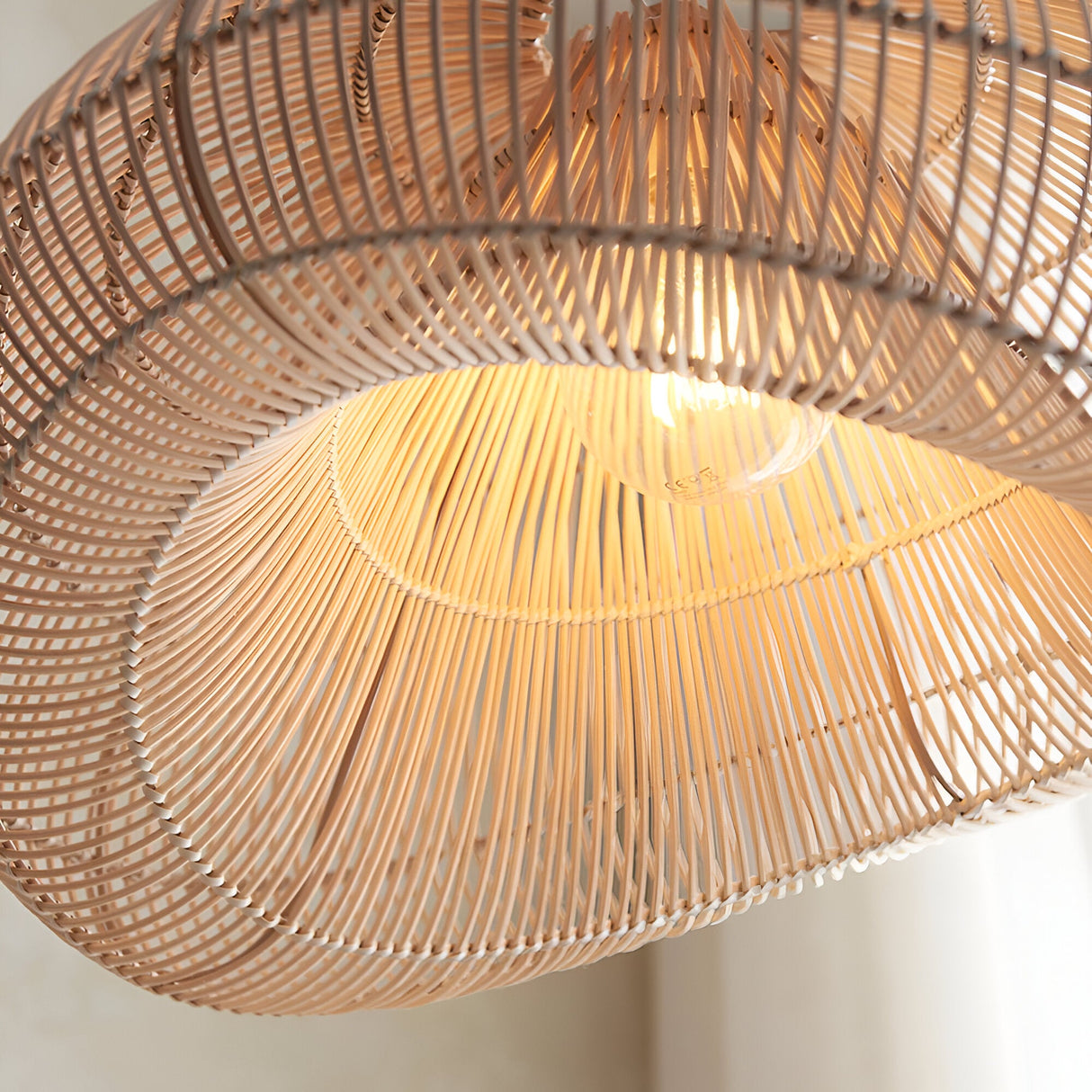 Close-up of the Endon Carlmere natural rattan pendant shade, showing the hand-woven cloud form and illuminated E27 bulb filtering through the open weave.