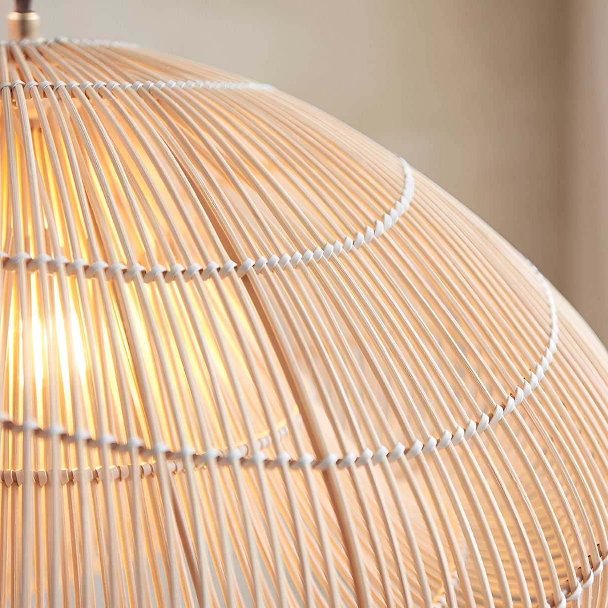 Close-up of the Endon Carlmere natural rattan pendant shade, showing the hand-woven cloud-shaped weave illuminated by a warm bulb.