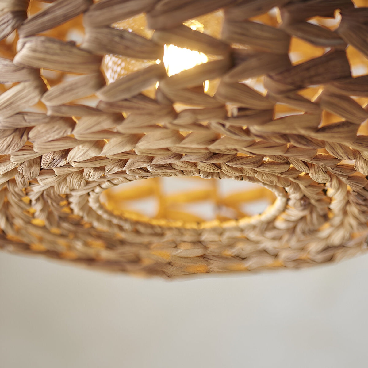 Close-up of the Endon Cranley natural handwoven rattan pendant shade, showing the open weave texture and illuminated E27 bulb inside.