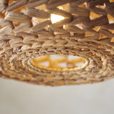 Close-up of the Endon Cranley natural handwoven rattan pendant shade, showing the open weave texture and illuminated E27 bulb inside.