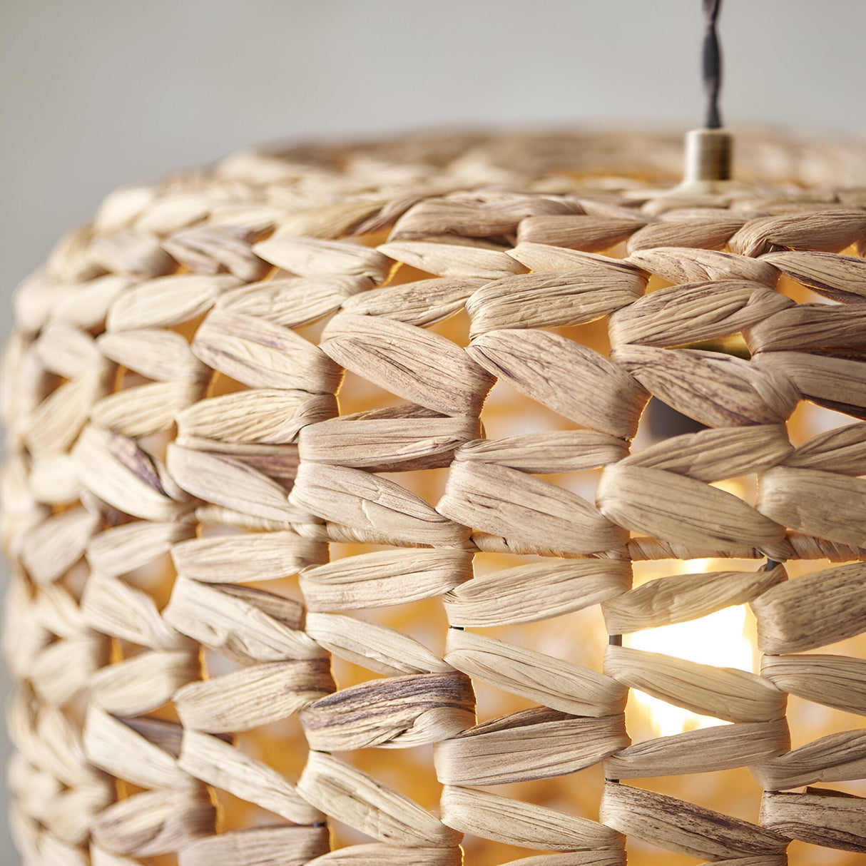 Close-up of the Endon Cranley pendant shade in natural, showing the handwoven rattan fibres in a chunky open weave with a warm bulb glowing inside.