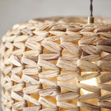 Close-up of the Endon Cranley pendant shade in natural, showing the handwoven rattan fibres in a chunky open weave with a warm bulb glowing inside.