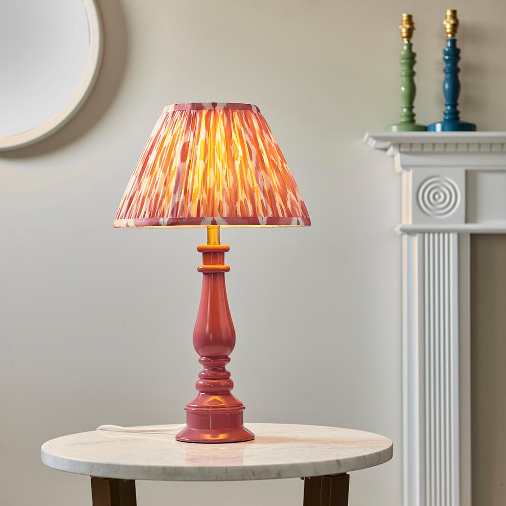 Endon Carlworth table lamp with pink gloss turned spindle base and brass holder, topped with a pink patterned pleated shade, on a marble side table.