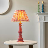 Endon Carlworth table lamp with pink gloss turned spindle base and brass holder, topped with a pink patterned pleated shade, on a marble side table.