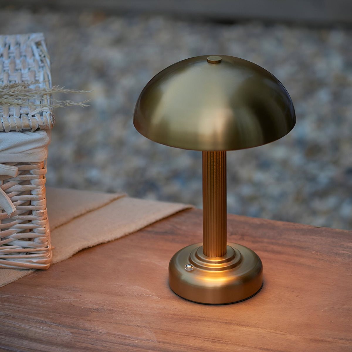 Endon Ashfield LED table lamp in brass with domed mushroom shade and fluted stem, shown on a wooden surface beside a woven basket.