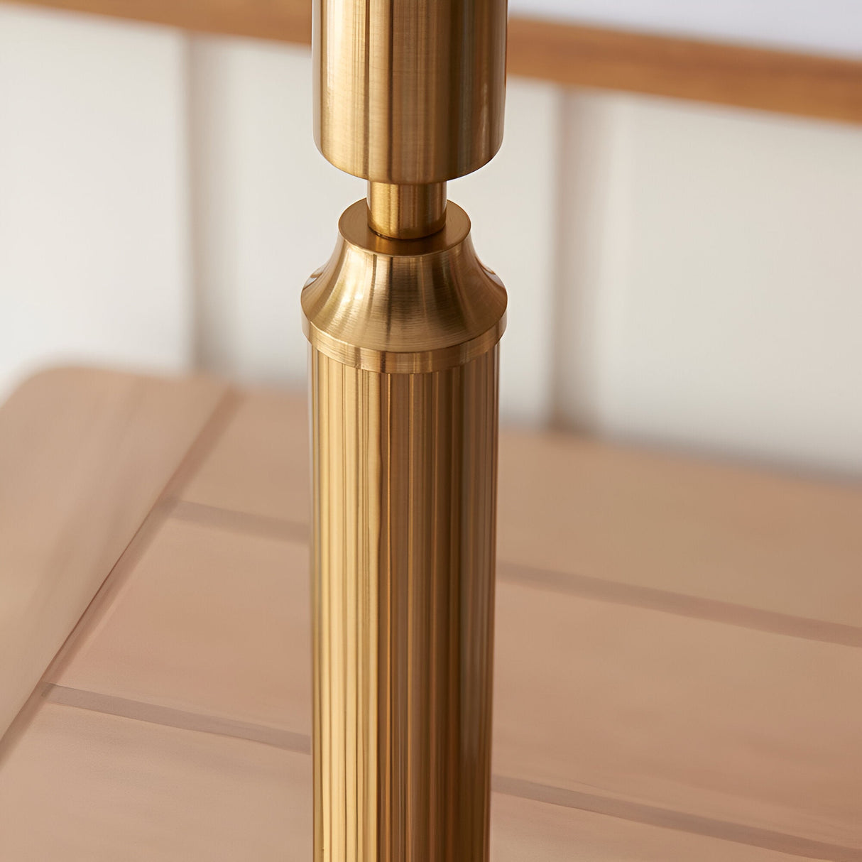 Close-up of the Endon Cranwick LED table lamp's brushed aged brass reeded stem rising from a square base on a light wooden surface.