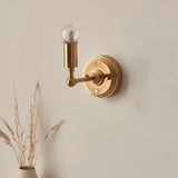 Endon Ashstead rechargeable wall light in aged brass with a slim arm, exposed LED globe bulb, and round backplate, mounted on a neutral wall.