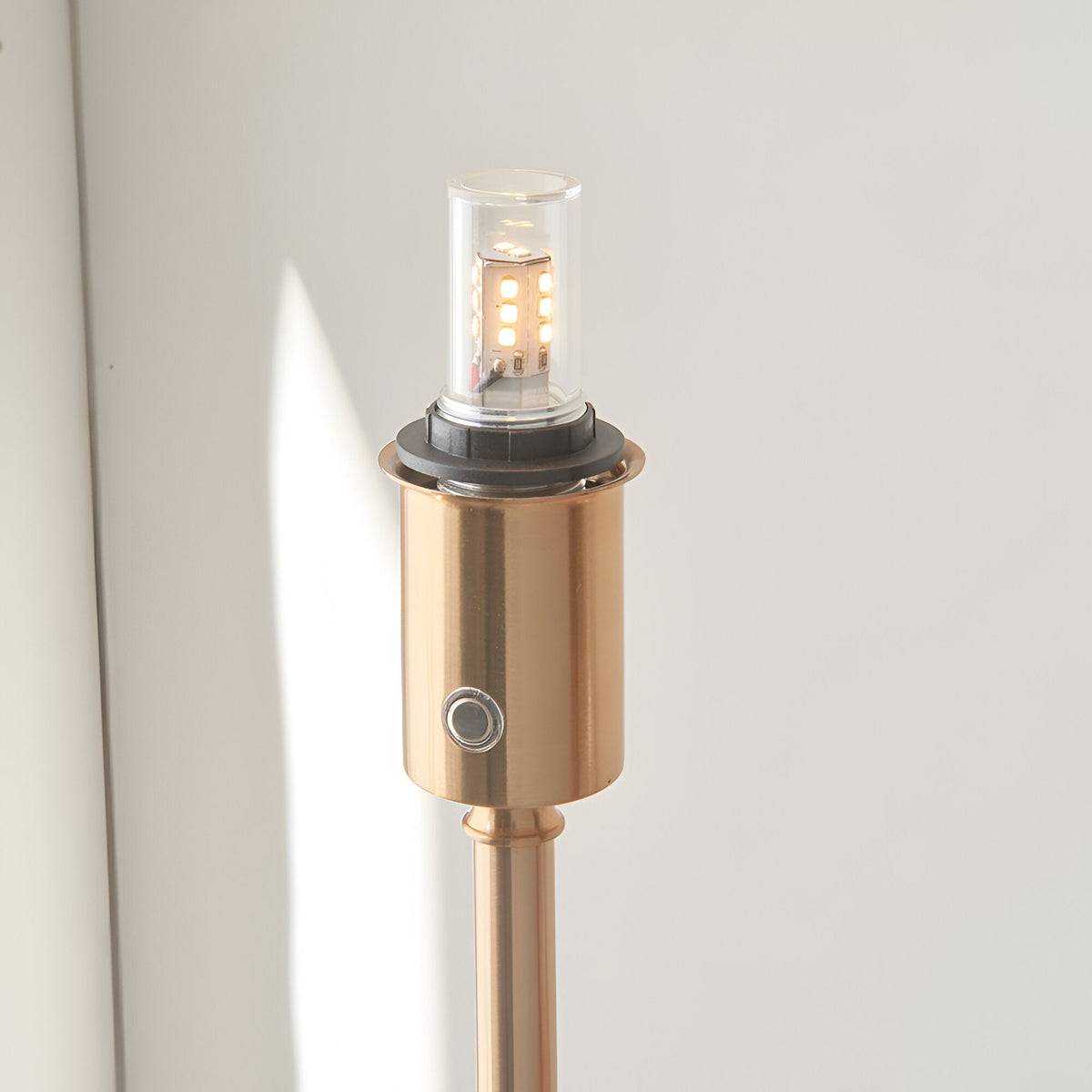 Close-up of the Endon Ashstead LED rechargeable floor lamp's aged brass holder, showing the integrated LED bulb and touch dimmer button.