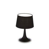 The Arc Small Table Lamp - Black features a wide, round base and a black fabric lampshade that embody a minimalist aesthetic. Positioned perfectly against a white background, it effortlessly complements modern interiors.