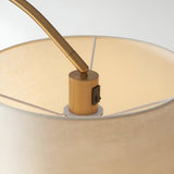 Close-up of Endon Bevbourne floor lamp showing brass lamp holder with black switch, tilting arm, and natural fabric shade interior.