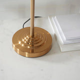 Brenley 3 Light Table Lamp base close-up in brushed brass with ribbed stepped design, shown beside white notepads on a marble surface.