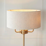 Brenley 3 Light Table Lamp in brass, with a round linen-mix drum shade and brushed metallic inner lining atop a slender brass base.