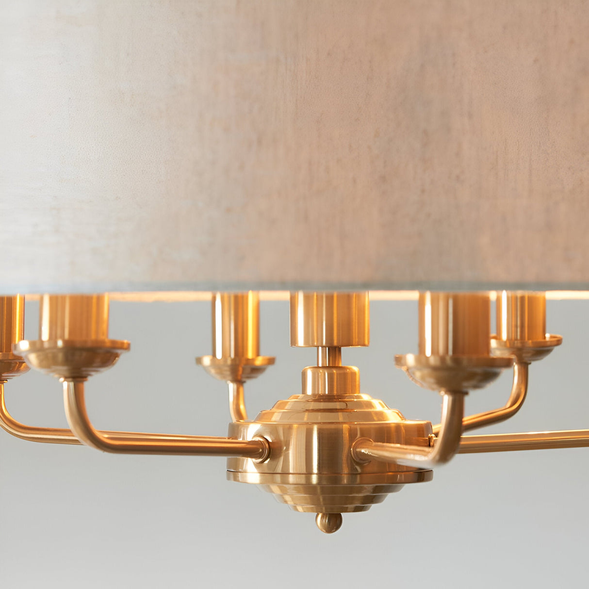 Close-up of Endon Brenley 6 Light Pendant in vintage brass, showing the six E14 lamp holders on curved arms beneath a natural linen shade.