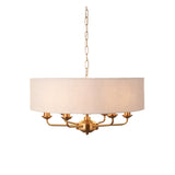 Endon Brenley 6 light pendant in vintage brass with a large natural linen drum shade, suspended from a chain on a plain white background.