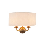 Endon Brenley 2 light wall light with natural linen drum shade and vintage brass twin-arm fitting, shown on a plain white background.