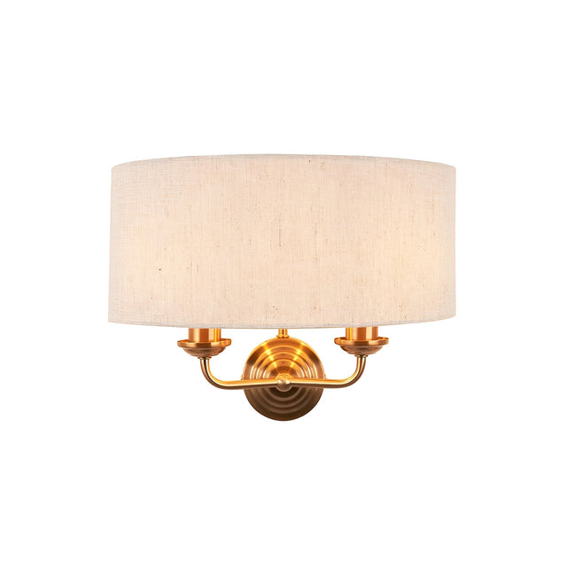 Endon Brenley 2 light wall light with natural linen drum shade and vintage brass twin-arm fitting, shown on a plain white background.