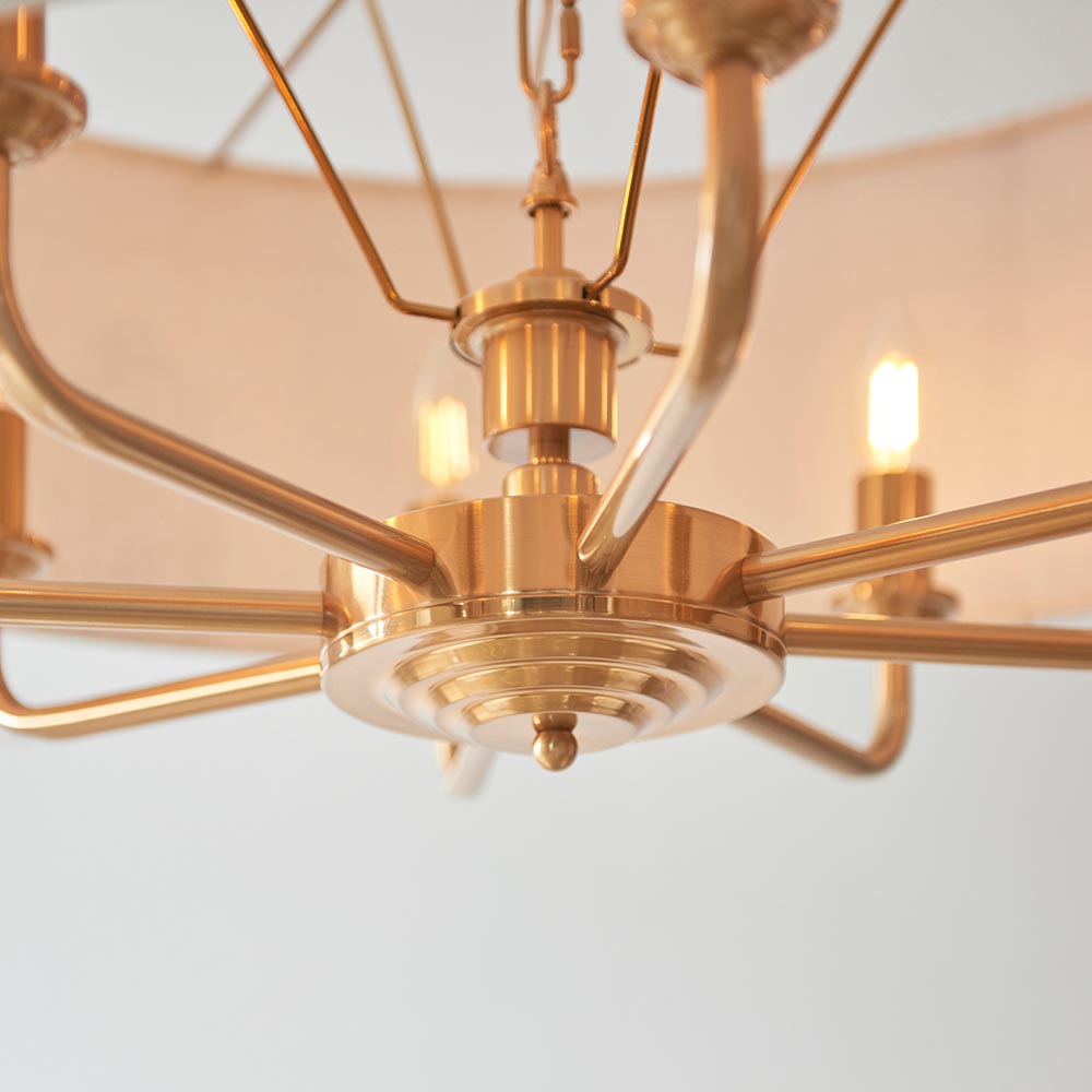 Close-up of the Endon Brenley 8 Light Pendant in vintage brass, showing the central hub, radiating arms, and two lit E14 candle lamps.