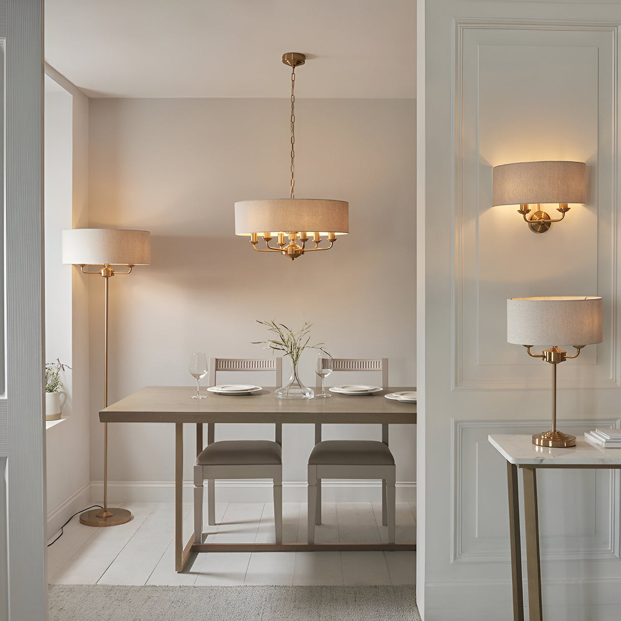 Endon Brenley brass table lamp with drum shade on a console, shown with matching floor lamp, pendant and wall light in a neutral dining room.