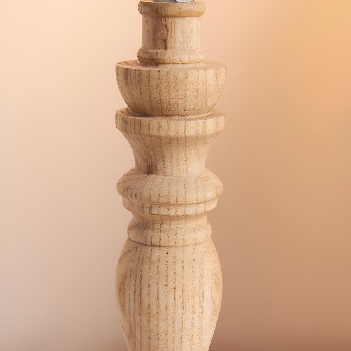 Close-up of the Endon Aldworth table lamp's turned natural ash wood spindle base with brass B22 lampholder, against a warm neutral background.