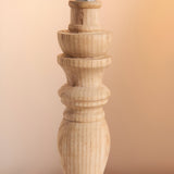 Close-up of the Endon Aldworth table lamp's turned natural ash wood spindle base with brass B22 lampholder, against a warm neutral background.