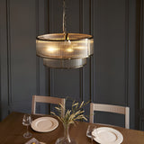 Endon Rothbury 5-light antique brass pendant with two tiers of clear ribbed glass shades, chain-hung above a dining table against panelled grey walls.