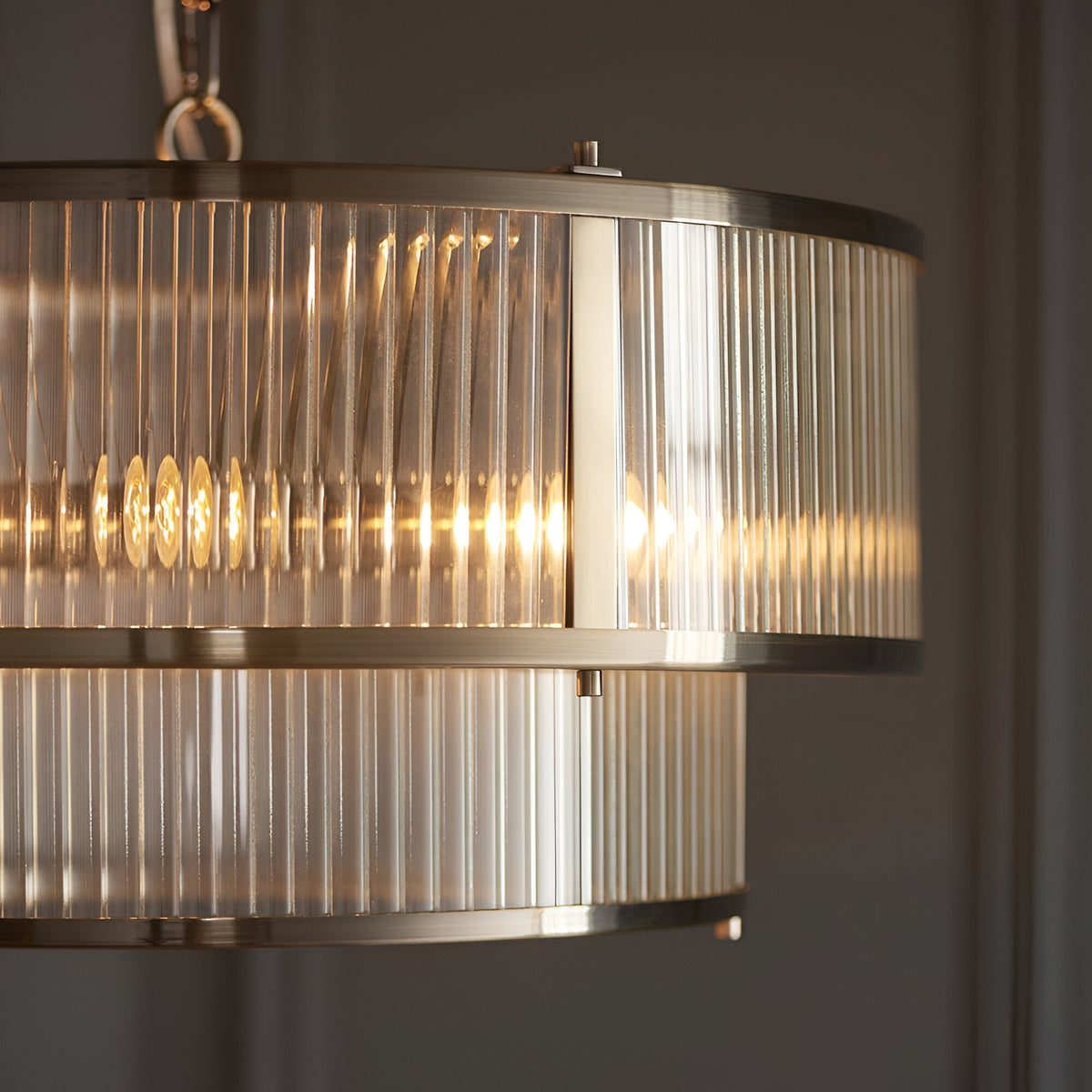 Close-up of Endon Rothbury 5 Light Pendant in antique brass, showing the double tier design with clear ribbed glass panel shades and lit lamps within.