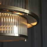 Close-up of the Endon Rothbury 5 Light Pendant in antique brass, showing the tiered ribbed glass shades and illuminated E14 lamps within.