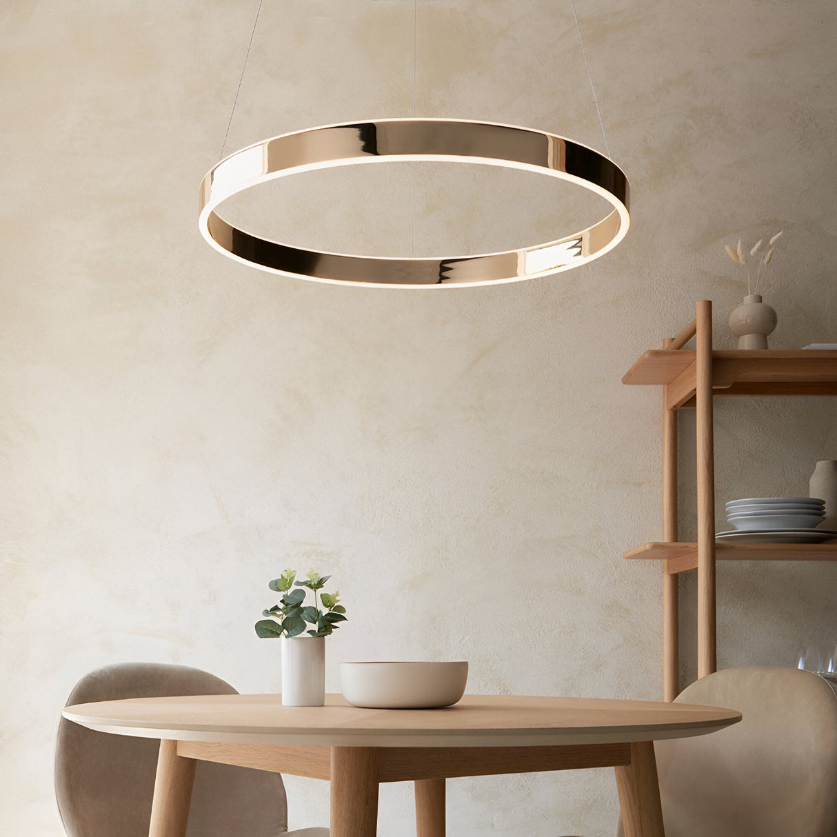 Endon Bramford LED ring pendant in warm French gold with frosted diffuser, suspended on wire cables above a wooden dining table in a neutral room.