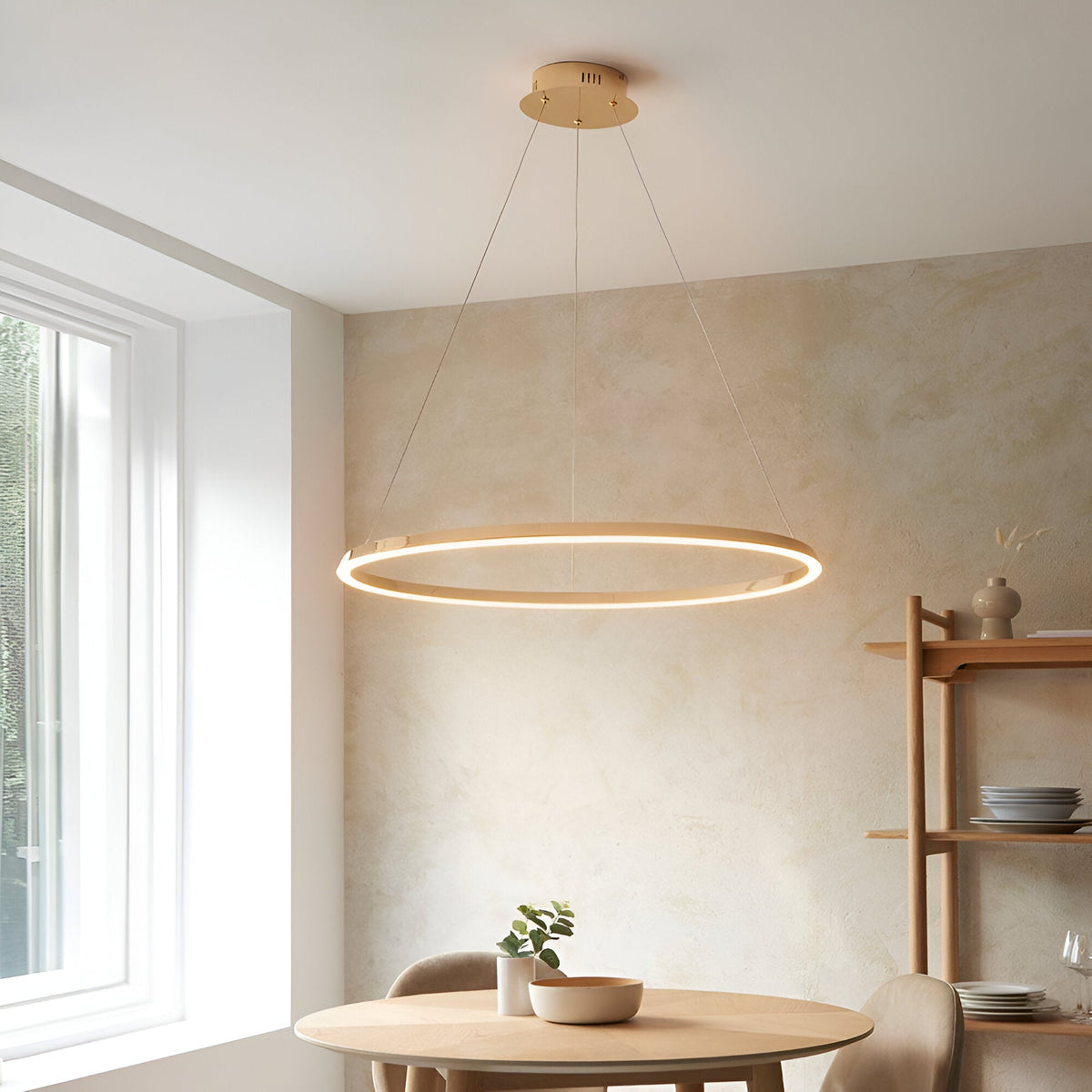 Cliffton LED Pendant in gold, a large circular ring light with white diffuser suspended on fine cables above a dining table in a neutral-toned room.