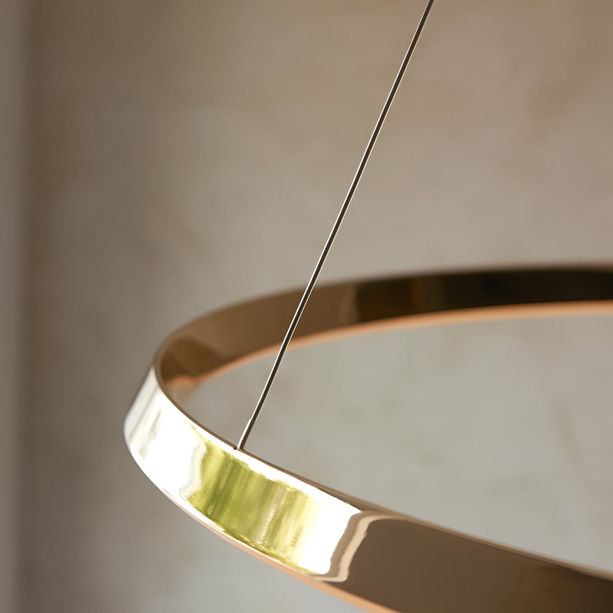 Close-up of the Cliffton LED Pendant in gold, showing the glossy ring frame, white diffuser, and slim suspension cable against a neutral background.