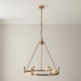 Endon Bevford 6 light hoop pendant in aged brass with six B22 lamp holders, suspended from a chain with black fabric flex against a pale wall.