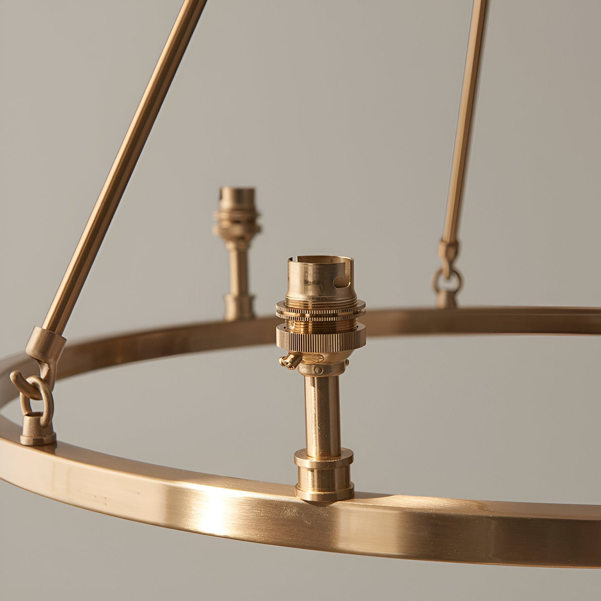 Close-up of the Endon Bevford 6 Light Pendant showing aged brass hoop with authentic B22 lamp holders and slender suspension rods against a neutral background.
