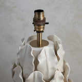 Close-up of the Endon Caldford large table lamp showing the aged brass B22 lamp holder atop the cream ceramic base with crackle-glazed leaf detailing.