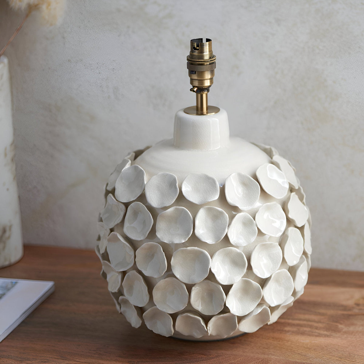 Endon Ashbury cream ceramic table lamp base with sculpted petal texture and aged brass B22 holder, on a wooden surface.