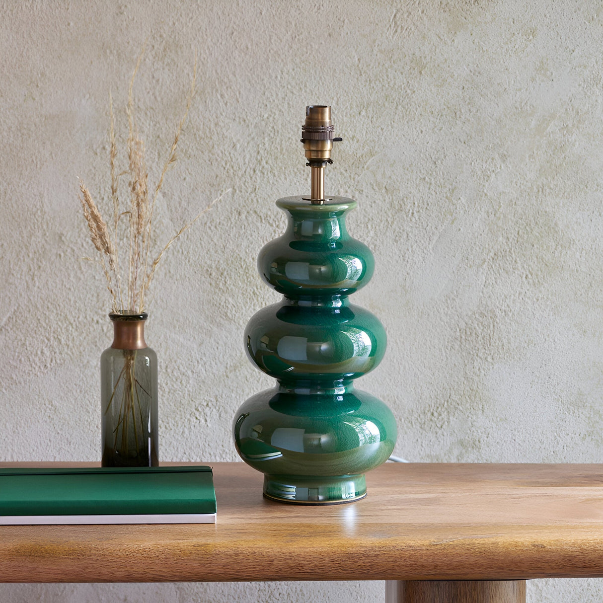 Endon Carlstead gourd-shaped ceramic table lamp base in gloss green reactive glaze with aged brass B22 holder, styled on a wooden console beside a vase.