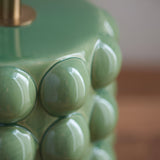 Close-up of the Endon Amberley table lamp base showing glossy green ceramic bobble texture and aged brass stem detail.