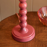 Close-up of the Endon Brenleigh table lamp base in glossy pink stacked metal spheres on a wooden side table beside a pink glass bowl.